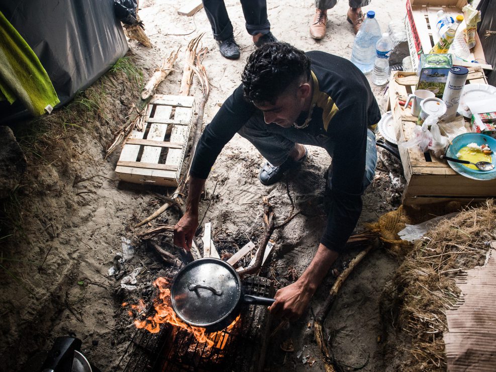 Un réfugié Pakistanais issu du Parachinar, Kurram Agency, région tribale à la frontière de l'Afghanistan, allume un feu dans la cabane qui lui sert de cuisine dans la new jungle de Calais.